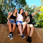three girls are sitting on a wall and laughing