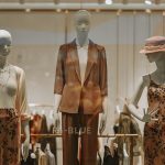 Three mannequins display fashionable clothing in a store window.