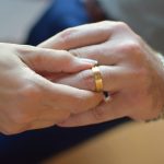 Une main glisse un anneau d'or sur le doigt d'une autre main