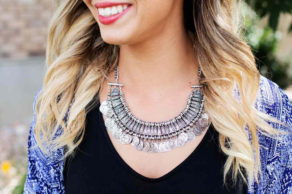 Une femme aux cheveux blonds porte un collier argenté imposant Une femme aux cheveux blonds porte un collier argenté imposant