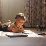 Un bébé joue au sol avec un livre et des jouets colorés